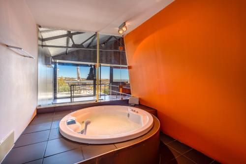 eine große Badewanne im Bad mit einem großen Fenster in der Unterkunft The Loft - a birdwatchers paradise in Fuseta