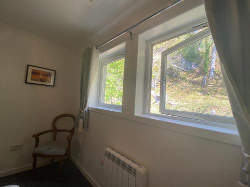 a room with two windows with a chair and a radiator at Barriemore Oban in Oban