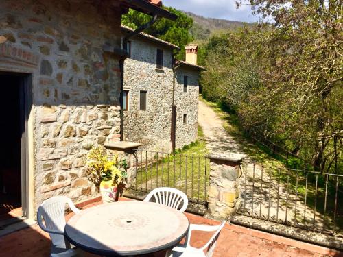 a patio with a table and chairs and a stone building at Agriturismo Fattoria Celle in Figline Valdarno