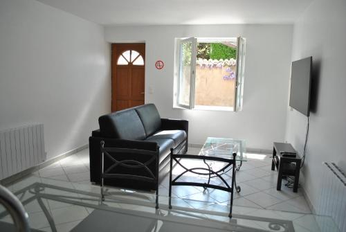a living room with a black chair and a glass table at L'HIRONDELLE in Saint-Laurent-de-Mure