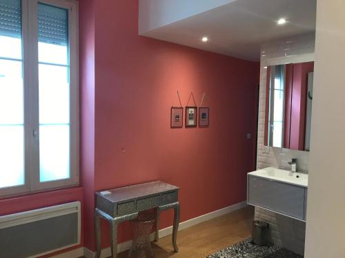 La salle de bains est pourvue de murs rouges, d'un lavabo et d'une fenêtre. dans l'établissement Le Vieljeux, Vieux port La Rochelle, à La Rochelle