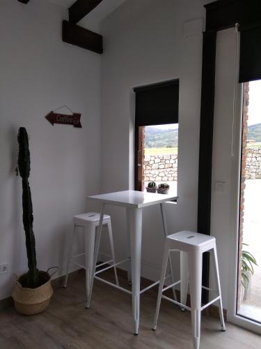a white table and stools in a room with a window at Posada Tresvalle in Ubiarco