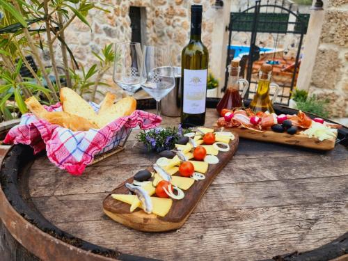 a table with cheese and bread and bottles of wine at Ivićev san in Tučepi