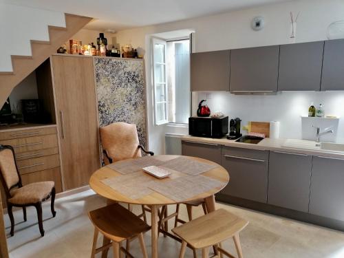 uma cozinha com uma mesa e cadeiras numa cozinha em 12 Rue des Ecoles em Saint-Émilion