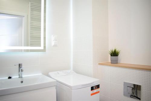 a white bathroom with a sink and a toilet at Apartos Apartamenty Grano Residence in Gdańsk