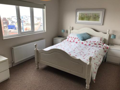 a bedroom with a white bed and two windows at West Strand View in Portrush