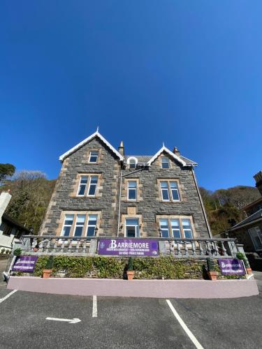 a large stone building with a purple sign on it at Barriemore Oban in Oban