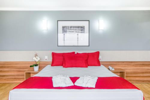 a bedroom with a large white bed with red pillows at Iate Hotel Centro Florianópolis in Florianópolis