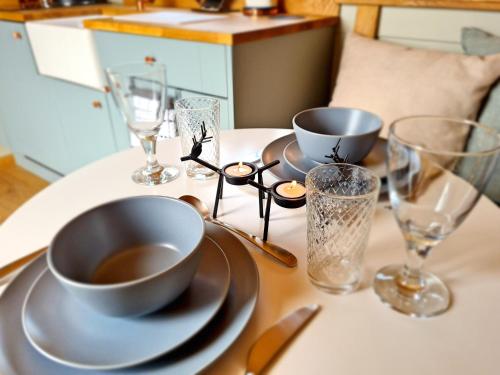 a table with plates and cups and glasses on it at Peak District Shepherds Hut in Hope