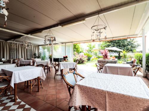 un restaurante con mesas y sillas blancas y ventanas en Hotel Zeno, en Cinquale