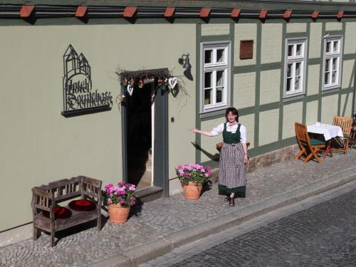 kobieta stojąca przed budynkiem w obiekcie Hotel Domschatz w mieście Quedlinburg