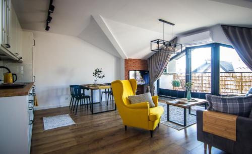 a living room with a yellow chair and a table at Apartamenty W37 in Nowy Targ