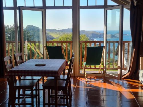 a dining room with a table and chairs and a balcony at Casa Tésera in El Franco