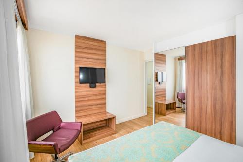 a hotel room with a bed and a chair and a tv at Iate Hotel Centro Florianópolis in Florianópolis