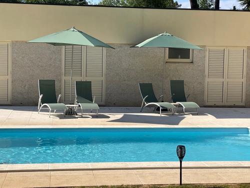 a pool with chairs and umbrellas next to a building at River house in Vila Nova Cerveira in Vila Nova de Cerveira