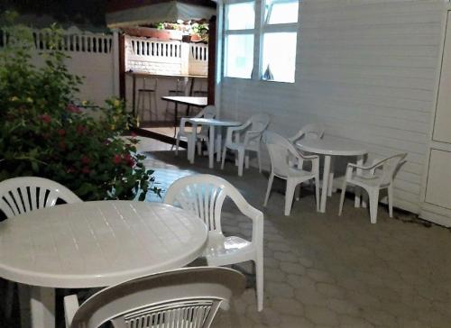 アナパにあるЧастный коттедж "Полинка"の白いテーブルと椅子が並ぶパティオ