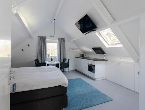 a white bedroom with a bed and a desk and a table at Slapen bij Jansz in Kamperland