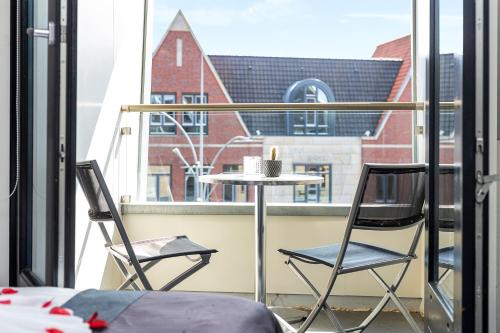 a table and two chairs on a balcony with a window at Hotel De Schout in Denekamp