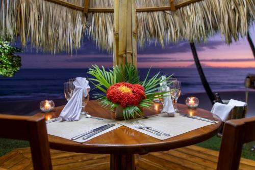 a table with a vase of flowers on top of the ocean at Tango Mar Beachfront Boutique Hotel & Villas in Tambor