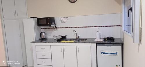 eine Küche mit einer Spüle und einer Mikrowelle in der Unterkunft Look Departamentos in Carhué