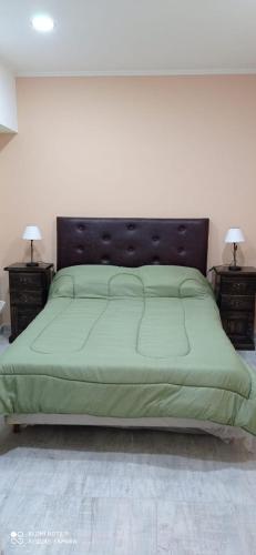 a bedroom with a green bed with two night stands at Look Departamentos in Carhué