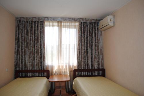 ヴォルシスキーにあるApartment on Pushkina 84のカーテン付きの窓が備わるドミトリールームのベッド2台分です。