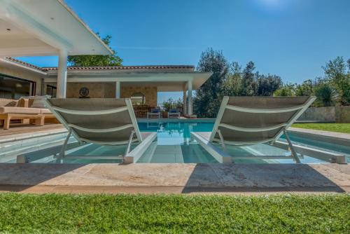 two chairs sitting next to a swimming pool at la villa miel in Opio