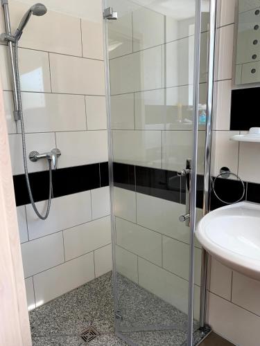 a shower with a glass door next to a sink at Gästehaus Nikita in Rust