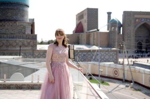 a woman in a pink dress standing on a balcony at Hotel Minor in Samarkand