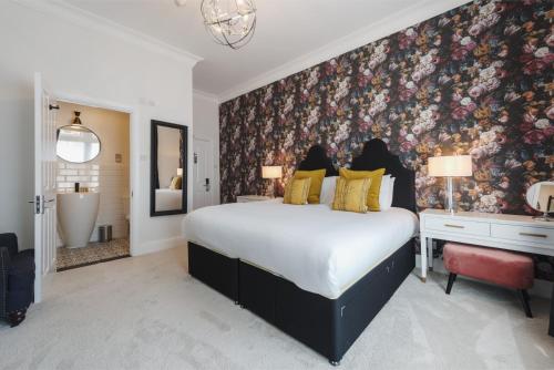 a bedroom with a large bed with a floral wallpaper at Somerset House Boutique Hotel and Restaurant in Portsmouth