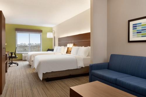 ein Hotelzimmer mit 2 Betten und einem Sofa in der Unterkunft Holiday Inn Express Hotel & Suites Opelika Auburn, an IHG Hotel in Opelika