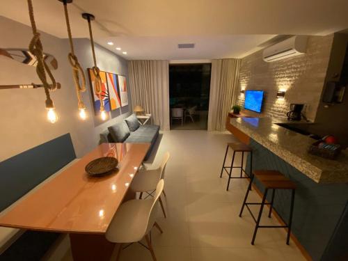 SOLARIS IMBASSAÍ في ايمباسّاي: مطبخ وغرفة معيشة مع طاولة وكراسي خشبية