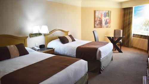 a hotel room with two beds and a table at Hotel San Luis Lindavista in Culiacán