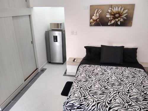 a bedroom with a black and white bed and a refrigerator at La Habitación Perfecta in Barranquilla