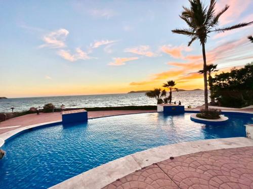 uma piscina ao lado da praia ao pôr do sol em Condominios Costa Diamante em San Carlos