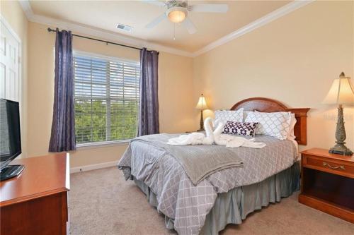 een slaapkamer met een bed, een tv en een raam bij COZY RESORT CONDO NEAR TOP ATTRACTIONS IN ORLANDO in Kissimmee