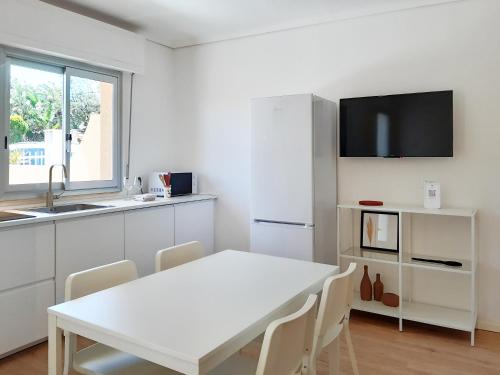 a white kitchen with a white table and a white refrigerator at PAPPA casa vacanze in Marina di Ragusa