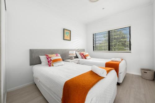 two beds in a bedroom with white walls and a window at Papillon Coolum in Coolum Beach