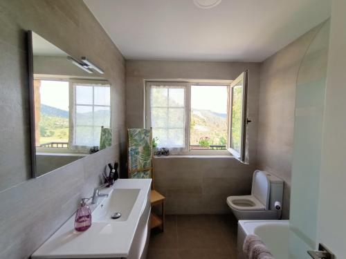 baño con lavabo, aseo y ventanas en El Mirador de Oter, en Oter