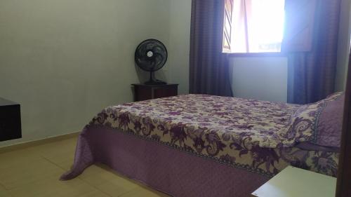 1 dormitorio con 1 cama, ventana y ventilador en Casa Caparaó, en Caparaó Velho
