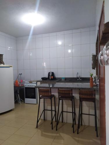 cocina con encimera y 3 taburetes en Casa Caparaó, en Caparaó Velho