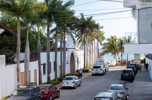 a street with parked cars and palm trees at Nereidas Lofts in Bucerías