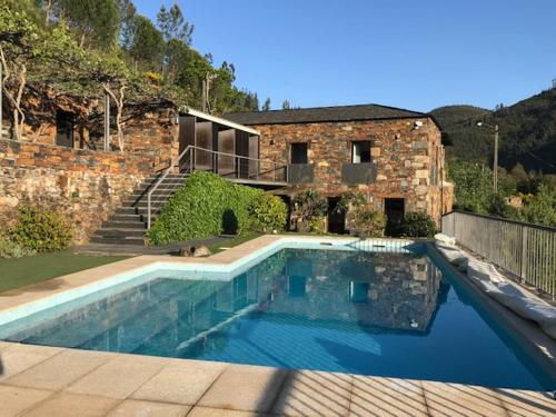 a swimming pool in front of a brick building at Passadiço Art and River House in Paradinha
