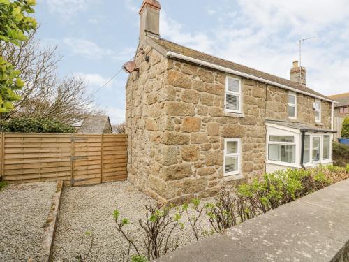 a stone house with a fence in front of it at Forge Cottage in Sennen