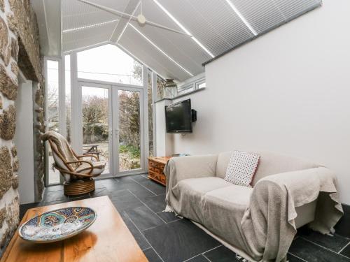 a living room with a couch and a tv at Forge Cottage in Sennen