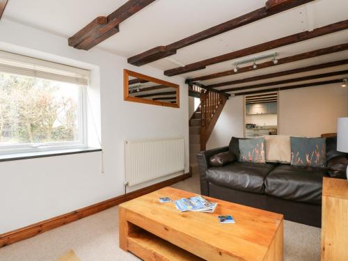 a living room with a leather couch and a table at Forge Cottage in Sennen