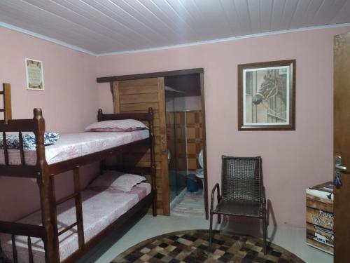 a room with two bunk beds and a chair at Rancho Velho Tropeiro in São Francisco do Sul