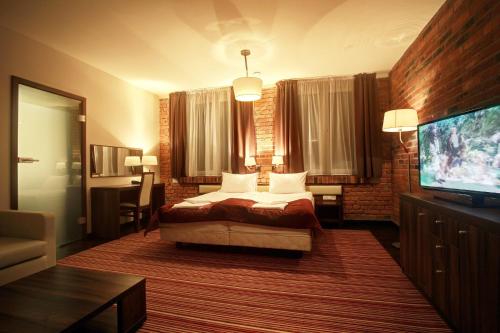 a bedroom with a bed and a flat screen tv at Browar CzenstochoviA Hotel&Spa in Częstochowa
