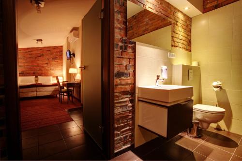 a bathroom with a sink and a toilet and a bedroom at Browar CzenstochoviA Hotel&Spa in Częstochowa