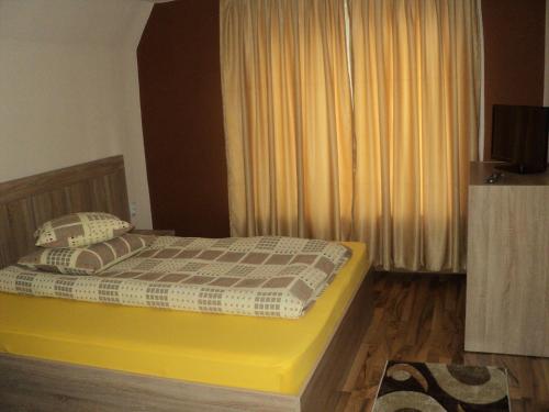 ein Schlafzimmer mit einem Bett mit gelbem Rahmen und einem Fenster in der Unterkunft Cabana Suvenirurilor in Scărişoara